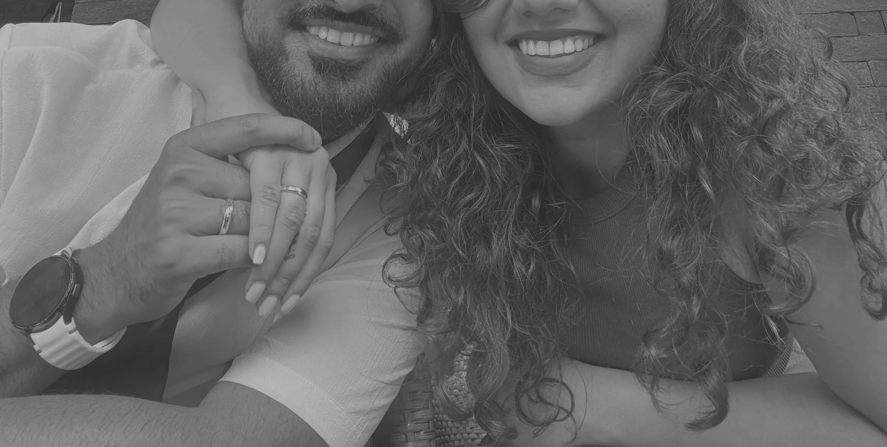 Tanya and Jason smiling, their hands together showing their rings.